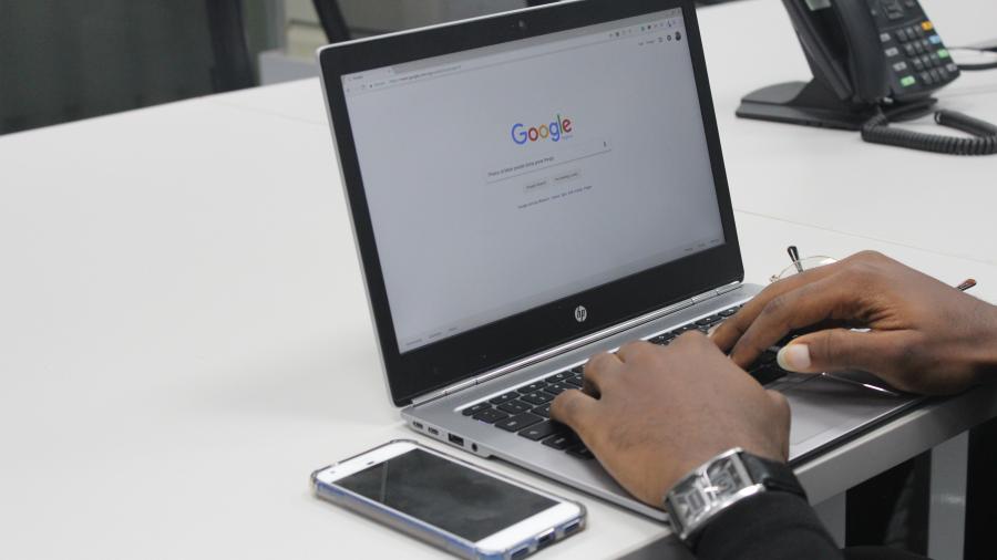 hands typing into Google on a laptop