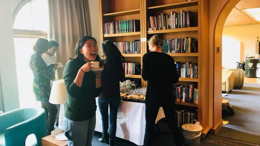 A wolfson student drinking coffee at an event, surrounded by others