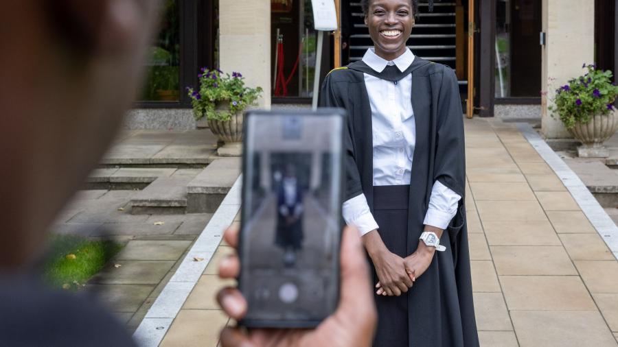 A student photgraphs their friend at graduation