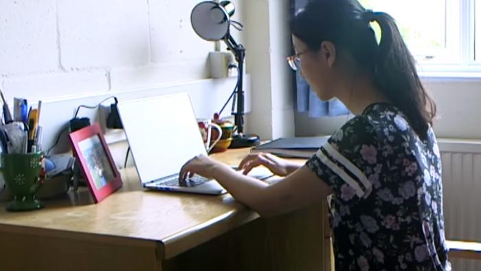 Woman sat at desk typing on a laptop