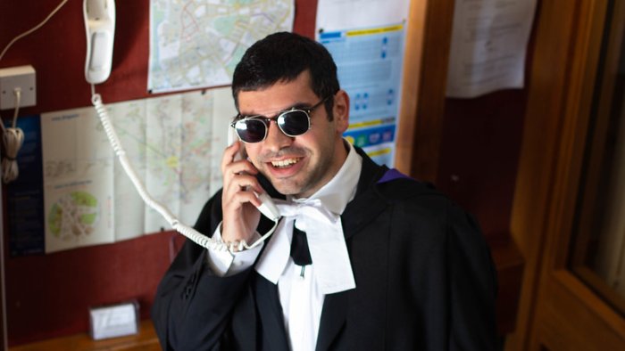 A wolfson graduand uses the phone in the porter's lodge