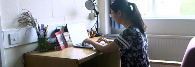 Woman sat at desk typing on a laptop