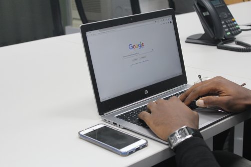 hands typing into Google on a laptop